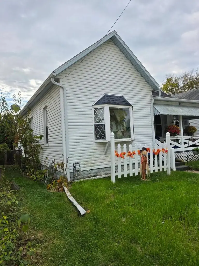 Completed exterior work on a white Ohio home in autumn, showing roof edge, gutters, and siding together