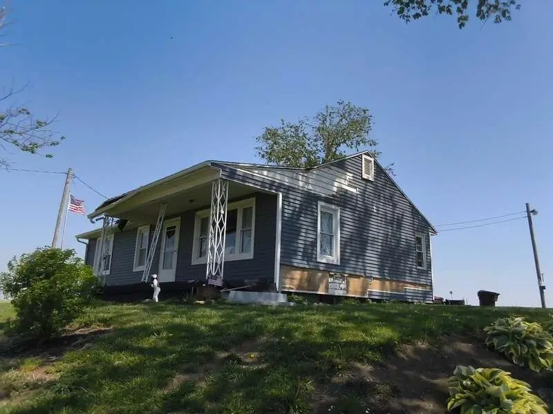 Completed asphalt shingle roof replacement with new gutters on a Central Ohio home under clear skies
