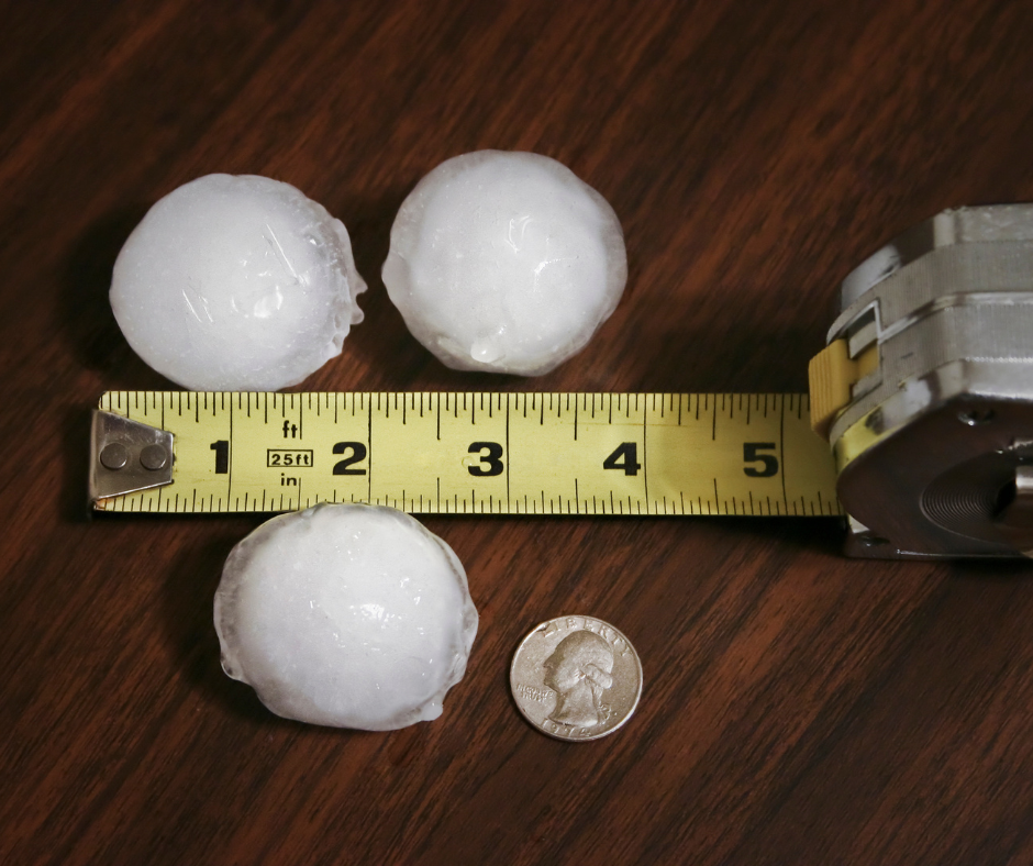 A handful of hailstones next to a tape measure and a quarter on a wooden porch, showing stone diameter after an Ohio thunderstorm.