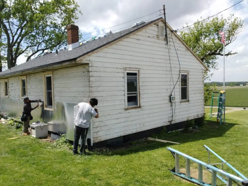 Failing painted wood siding with peeling paint on a rural Central Ohio ranch home before replacement