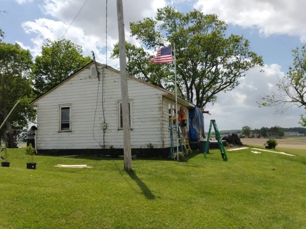 Kyline crew installing new siding panels over the original wall on a Central Ohio home, with a miter saw set up in the yard